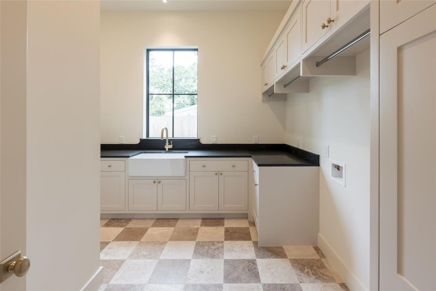 This elegant laundry room connects directly from the primary closet, creating a seamless daily routine. Classic checkered stone flooring, honed soapstone counters, and a deep farmhouse sink elevate both form and function. This elegant laundry room connects directly from the primary closet, creating a seamless daily routine. Classic checkered stone flooring, honed soapstone counters, and a deep farmhouse sink elevate both form and function.