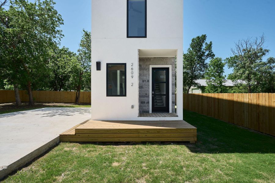Rear view of house with a yard, a fenced backyard, stucco siding, a patio area, and stone siding