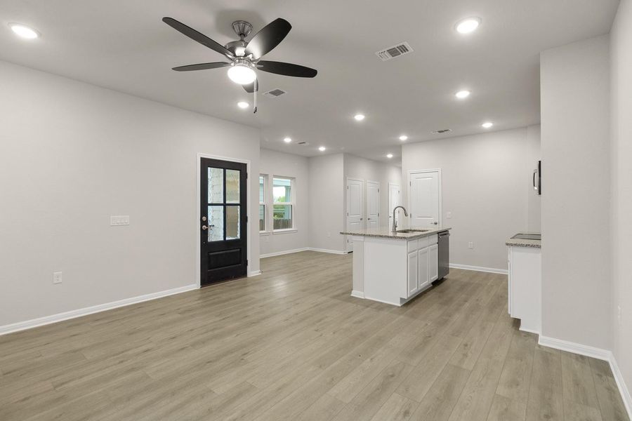 Spacious open concept living area featuring light-colored flooring, recessed lighting, and a modern ceiling fan
