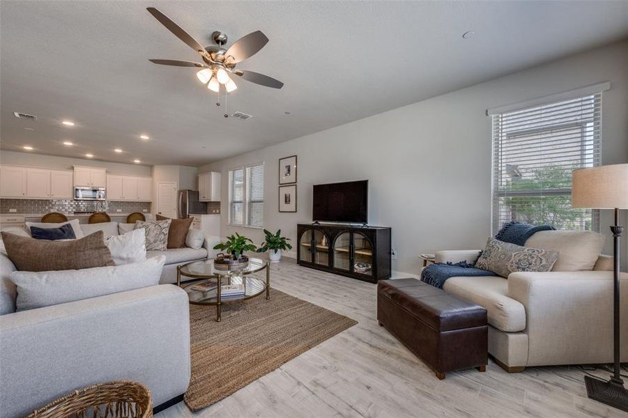 Expansive main living space with wide-plank flooring, oversized windows, and seamless connection to the kitchen.