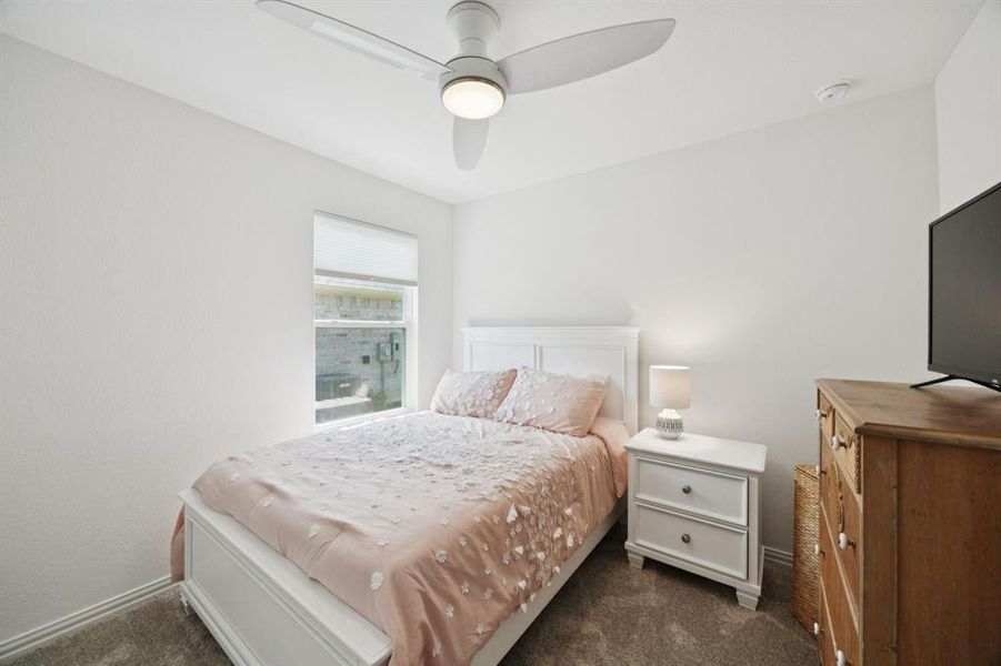 Split secondary bedroom features carpet and ceiling fan.