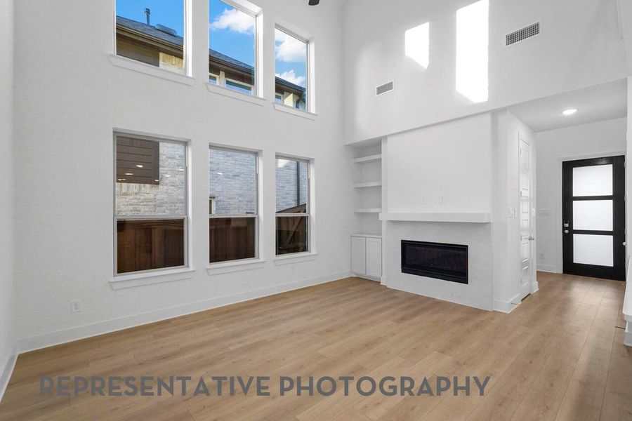 A bright and airy family room features soaring ceilings and expansive windows that flood the space with natural sunlight, creating a warm and inviting atmosphere.