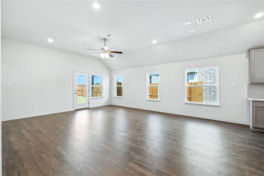 Unfurnished living room with dark wood finished floors, recessed lighting, lofted ceiling, and ceiling fan Unfurnished living room with dark wood finished floors, recessed lighting, lofted ceiling, and ceiling fan