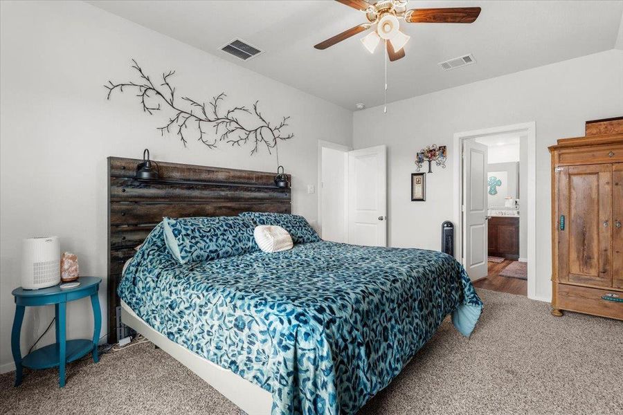 Carpeted bedroom with ceiling fan and ensuite bathroom