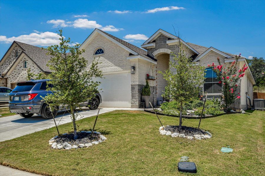 A neatly manicured lawn frames this charming home with an attached garage and a welcoming arched entryway. A neatly manicured lawn frames this charming home with an attached garage and a welcoming arched entryway.