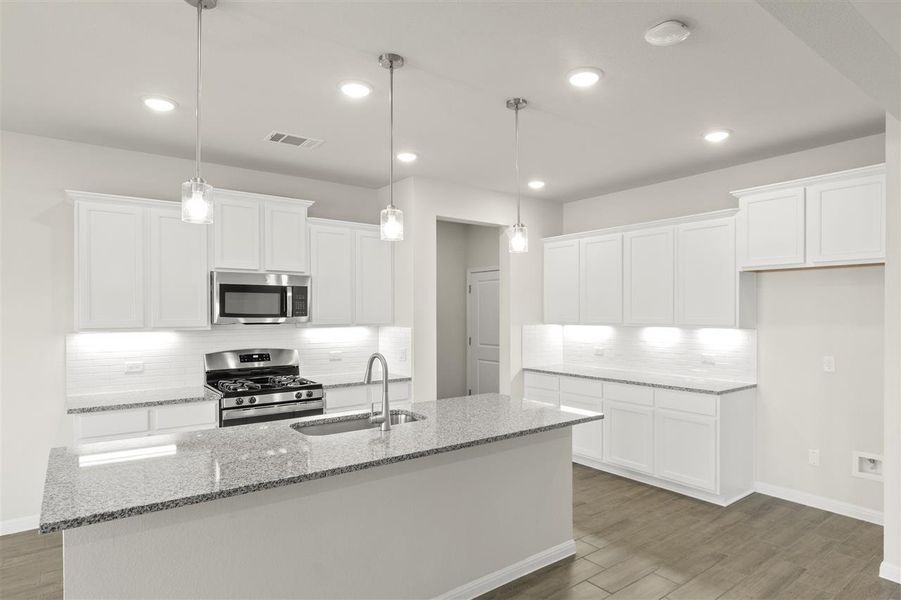 Kitchen with a sink, visible vents, wood finished floors, and stainless steel appliances