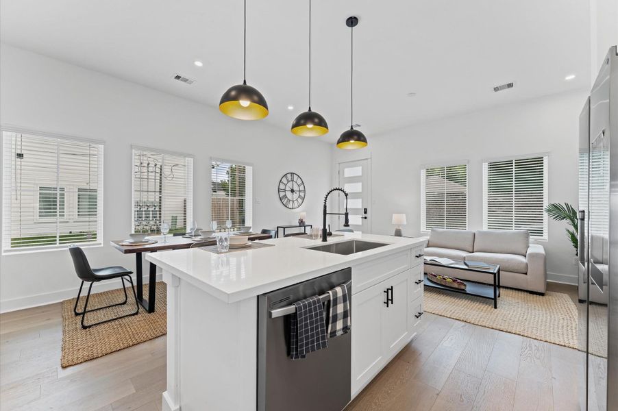 This centrally positioned kitchen island serves as a stylish anchor within the open-concept layout, offering clear sightlines to the dining area, living space, and the front yard. Its placement encourages seamless interaction, whether prepping meals or entertaining guests, while natural light pours in through the nearby windows. The island’s sleek design and functional surface make it a hub of activity, framed by elegant finishes tying together comfort and sophistication.