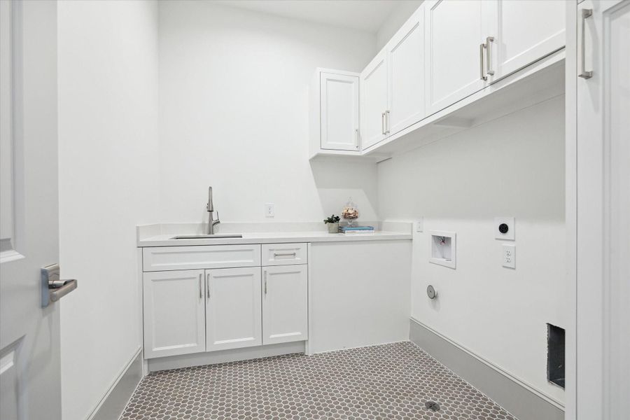 Second-floor utility room features Plover Carrara Quartz countertops, sink and cabinet storage.