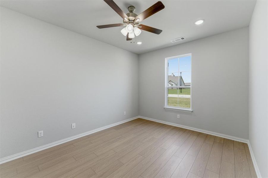 Room featuring light gray walls, wood-finish flooring, and a ceiling fan with integrated lighting Room featuring light gray walls, wood-finish flooring, and a ceiling fan with integrated lighting