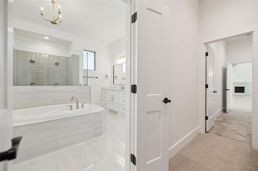 Bathroom featuring vanity, separate shower and tub, and a notable chandelier