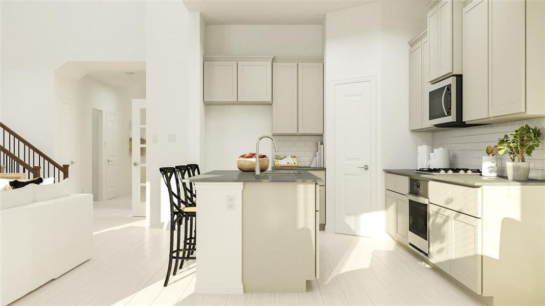 Kitchen featuring appliances with stainless steel finishes, backsplash, a center island with sink, and sink