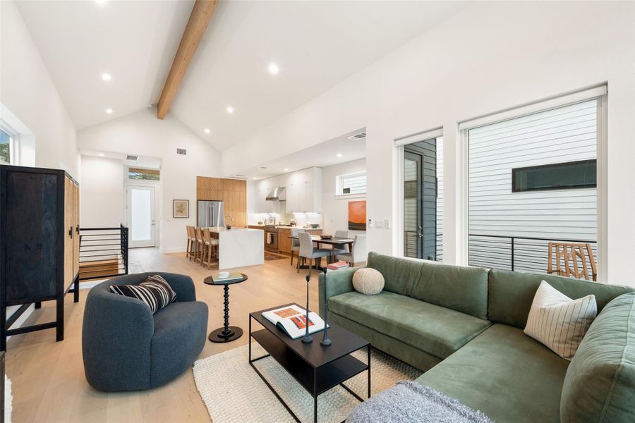 A well-lit open-concept living area with vaulted ceilings and a modern kitchen. A well-lit open-concept living area with vaulted ceilings and a modern kitchen.