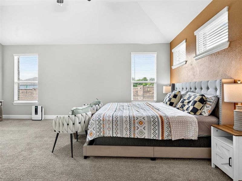Carpeted room featuring multiple windows with blinds, a vaulted ceiling, and textured accent wall Carpeted room featuring multiple windows with blinds, a vaulted ceiling, and textured accent wall