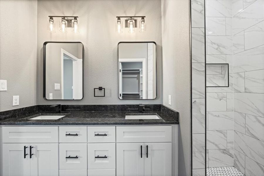 Bathroom with double vanity sink, dual mirrors, modern finishes and tiled shower