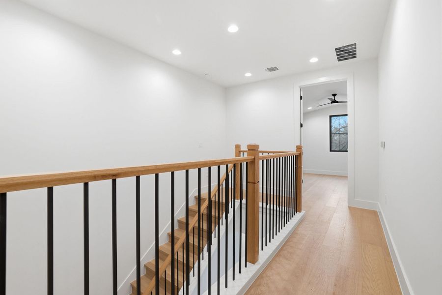 Hallway with recessed lighting, light wood-style flooring, and an upstairs landing