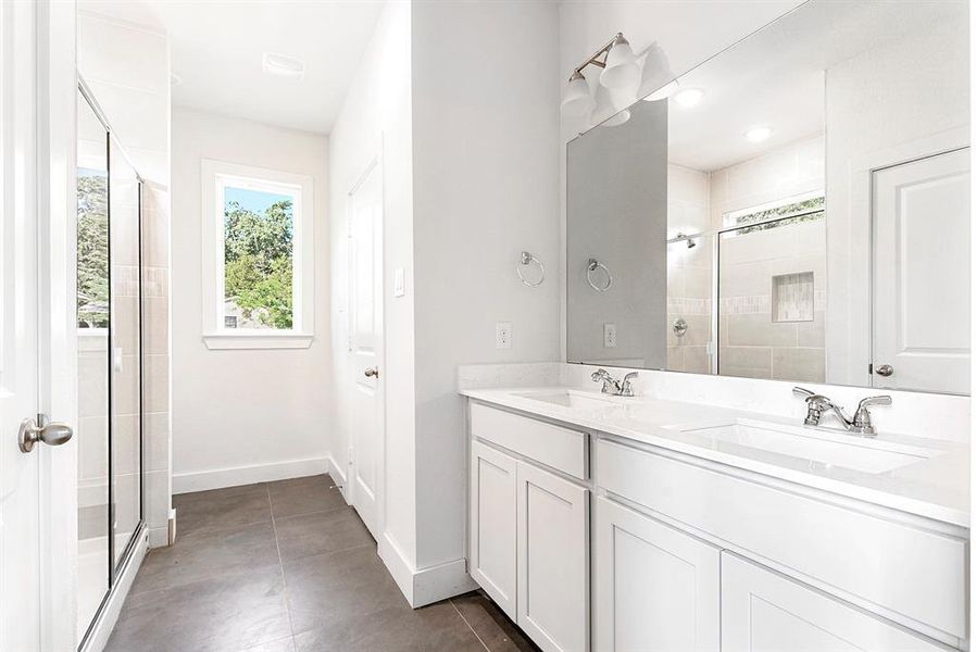 Primary bathroom-Large tile flooring, his/her sinks, quartz countertops, large stand alone shower, and window in bathroom.