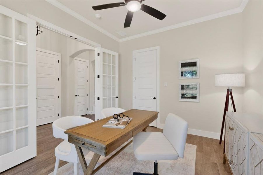Versatile interior space featuring French doors with glass panes, wood-finish flooring, a ceiling fan with integrated lighting, crown molding, and a solid panel door with black hardware