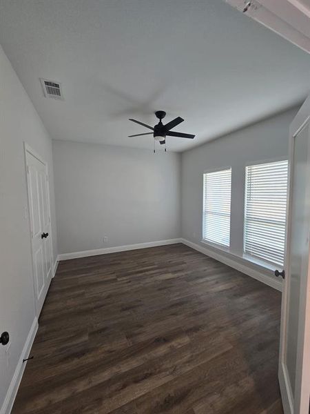 Unfurnished bedroom featuring dark wood-style floors and a ceiling fan