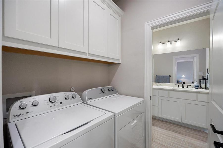 Laundry area with light wood-type flooring, washer and clothes dryer, and cabinet space