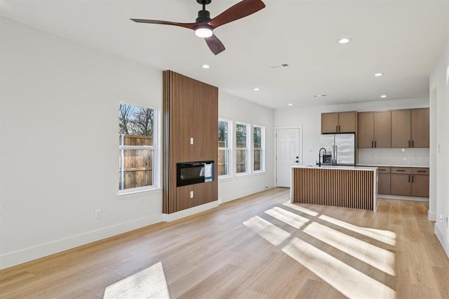 Kitchen featuring a kitchen island with sink, open floor plan, light wood-type flooring, recessed lighting, and stainless steel fridge with ice dispenser