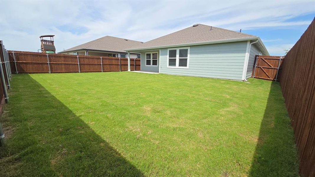 Expansive rear yard featuring a green lawn, privacy fencing, and a side access gate Expansive rear yard featuring a green lawn, privacy fencing, and a side access gate