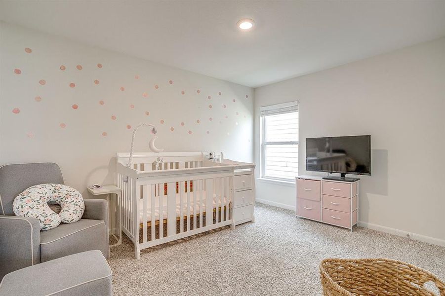 Bedroom featuring a nursery area and light carpet