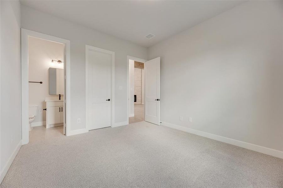 Unfurnished bedroom with carpet floors and connected bathroom