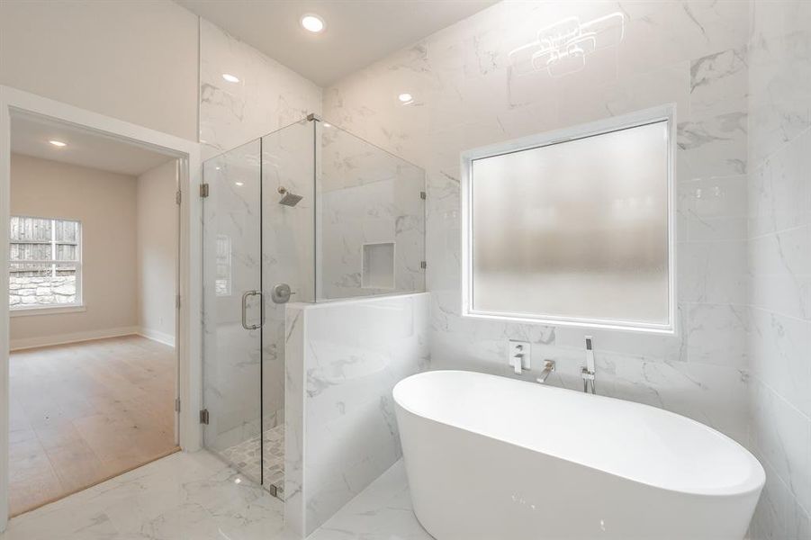 Full bath featuring marble tiled flooring, a freestanding bath, a marble finish shower, and recessed lighting