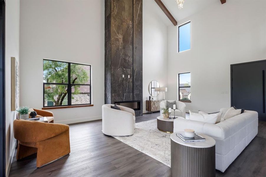 Living area featuring a floor-to-ceiling fireplace with stone surround, high ceilings, exposed wood beams, and dark wood-finish flooring Living area featuring a floor-to-ceiling fireplace with stone surround, high ceilings, exposed wood beams, and dark wood-finish flooring