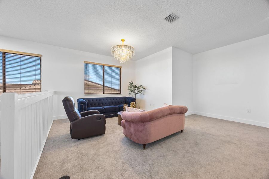 Living room featuring a chandelier, carpet floors, and a textured ceiling