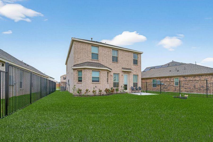 Premium lot with no rear neighbors, expansive lawn, extended concrete patio, and iron fencing.