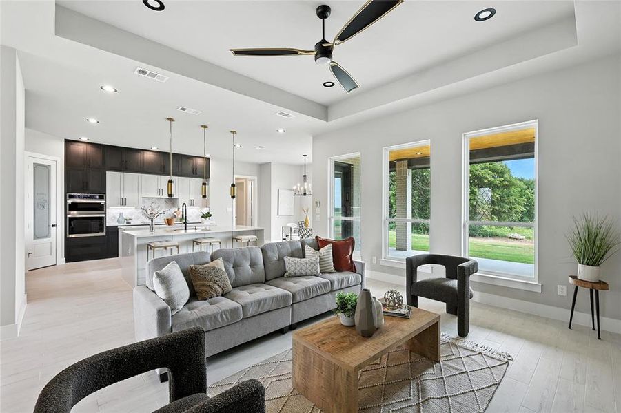 Living area featuring recessed lighting, a ceiling fan, light wood finished floors, a chandelier, and a tray ceiling