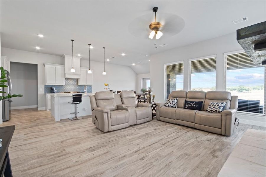 Living room featuring ceiling fan, a healthy amount of sunlight, light wood-type flooring, and lofted ceiling