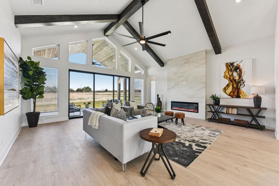 Living room featuring light wood finished floors, a high end fireplace, and a ceiling fan