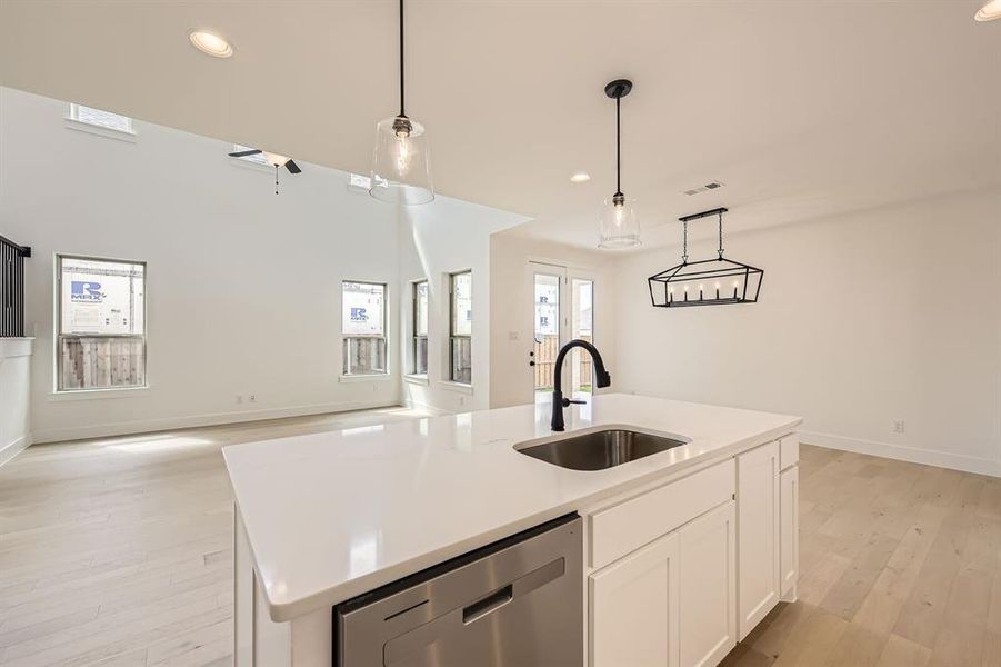 Kitchen with open floor plan, stainless steel dishwasher, light wood finished floors, a center island with sink, and recessed lighting Kitchen with open floor plan, stainless steel dishwasher, light wood finished floors, a center island with sink, and recessed lighting