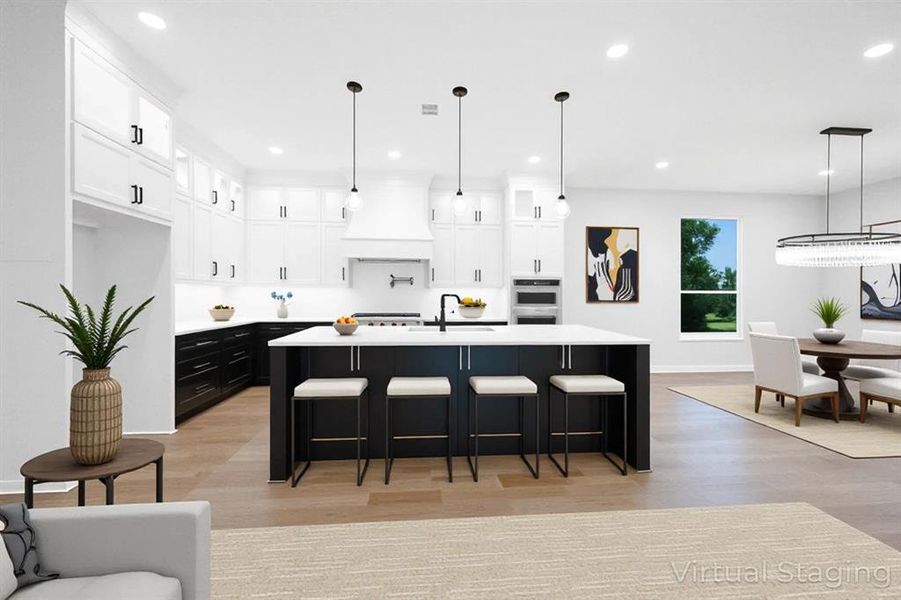 Kitchen with light wood-style floors, light countertops, recessed lighting, an island with sink, and white cabinetry Kitchen with light wood-style floors, light countertops, recessed lighting, an island with sink, and white cabinetry