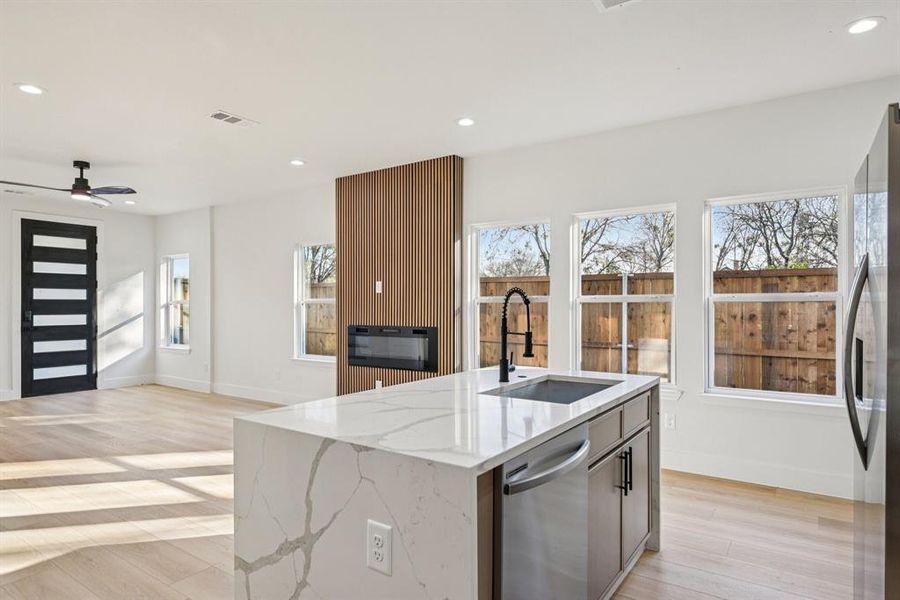Kitchen with light stone countertops, recessed lighting, light wood-style flooring, appliances with stainless steel finishes, and open floor plan