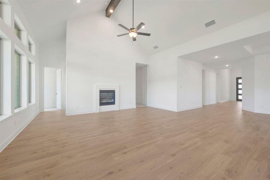 Spacious living area featuring high vaulted ceilings with exposed wood-finish beams, a ceiling fan, and recessed lighting Spacious living area featuring high vaulted ceilings with exposed wood-finish beams, a ceiling fan, and recessed lighting