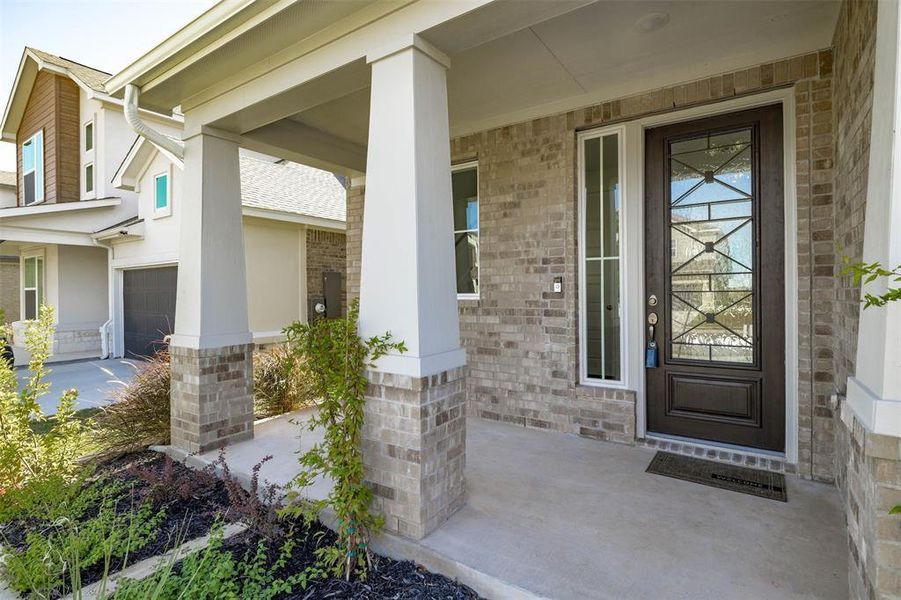 Entrance to property featuring a porch and brick siding Entrance to property featuring a porch and brick siding