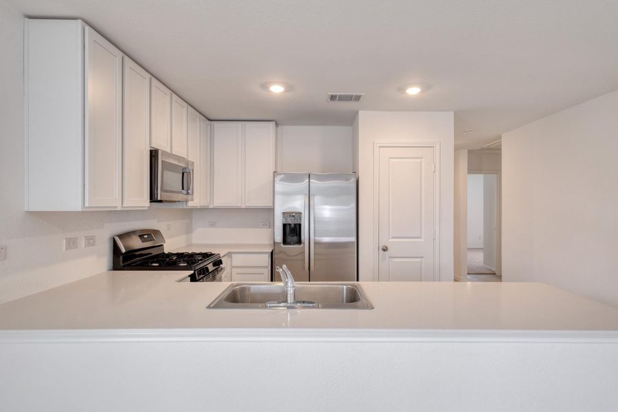 Kitchen featuring light-toned countertops, white cabinetry, and stainless steel appliances