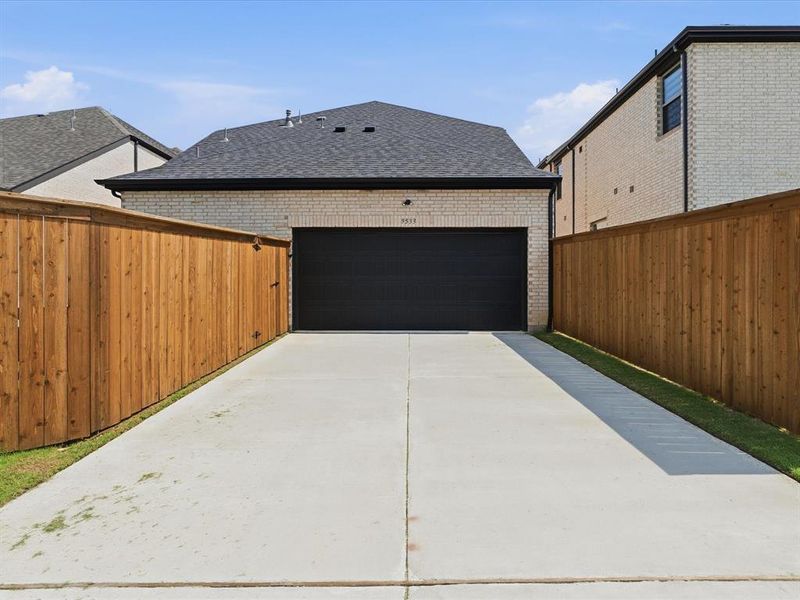 Rear-entry garage with an asphalt shingle roof and light-colored brick exterior