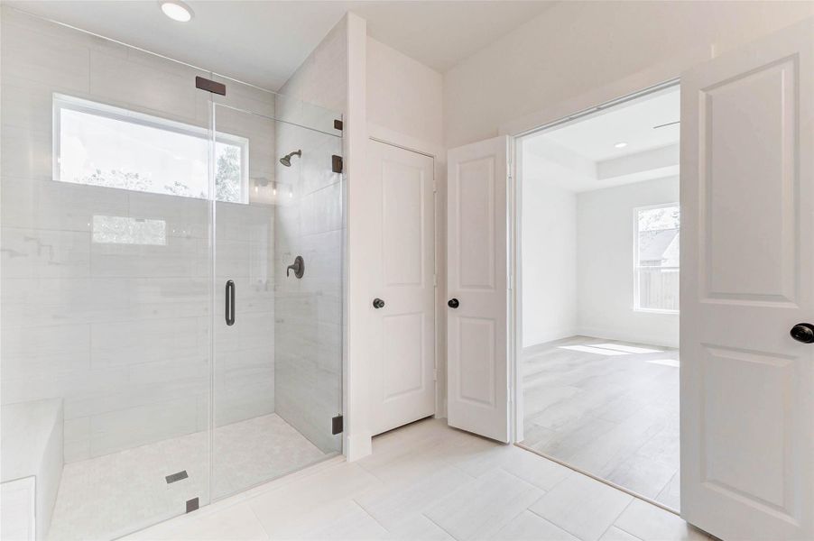 Spacious walk-in shower featuring a transom window, niche, and built-in bench.Large linen closet offers ample storage for all your essentials.