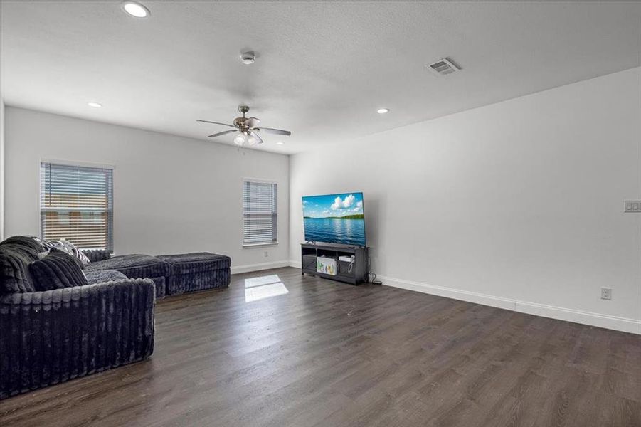 Living room featuring healthy amount of natural light, dark wood finished floors, recessed lighting, and a ceiling fan Living room featuring healthy amount of natural light, dark wood finished floors, recessed lighting, and a ceiling fan