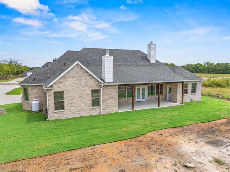 Back of property featuring a chimney, a lawn, a patio, and brick siding Back of property featuring a chimney, a lawn, a patio, and brick siding