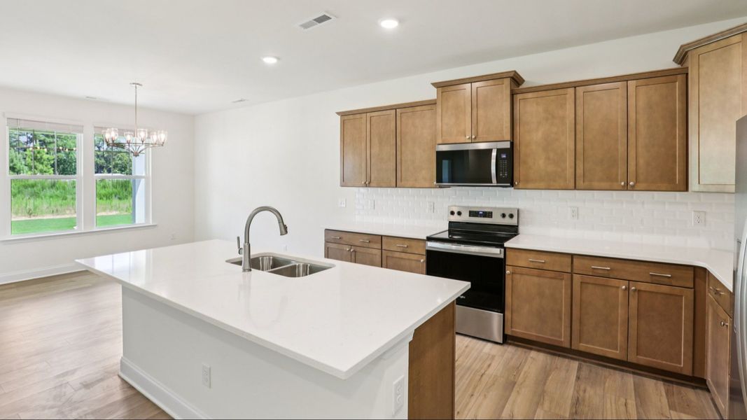 Pendleton home plan open concept kitchen with large island, tile backsplash and abundant cabinetry Pendleton home plan open concept kitchen with large island, tile backsplash and abundant cabinetry