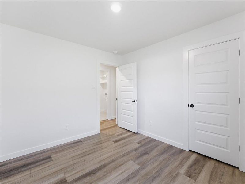 Bedroom featuring wood-finish flooring, crisp white walls, and a recessed ceiling light Bedroom featuring wood-finish flooring, crisp white walls, and a recessed ceiling light