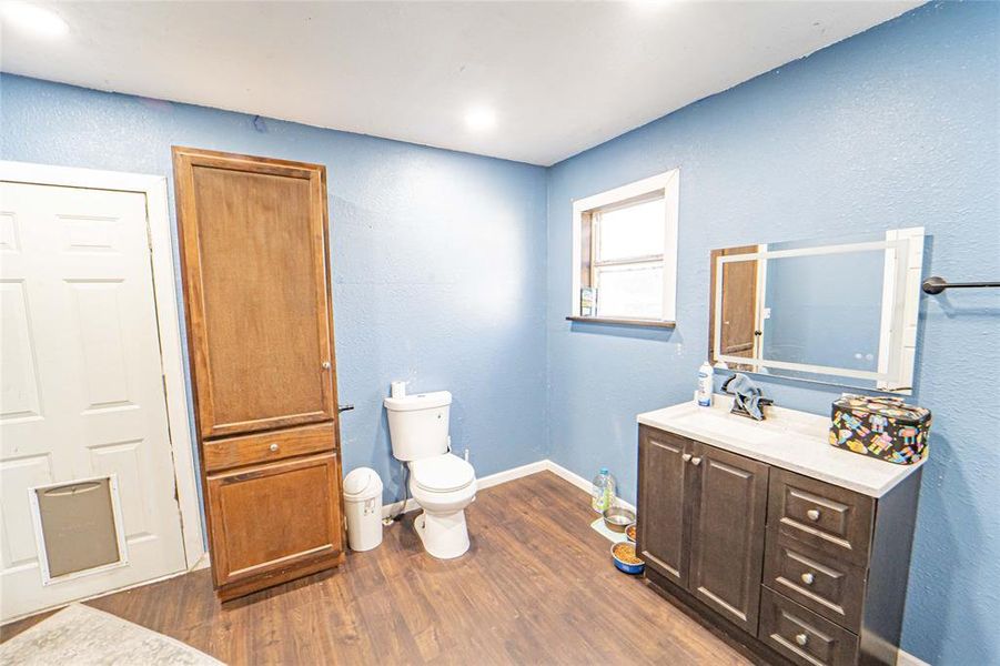 Full bathroom with a textured wall, dark wood-style floors, and vanity Full bathroom with a textured wall, dark wood-style floors, and vanity
