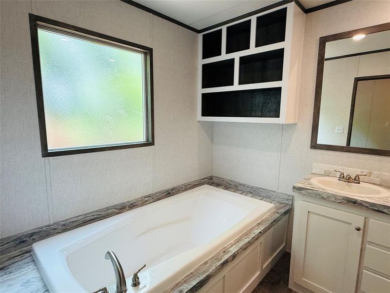 Full bath with a garden tub, crown molding, and vanity