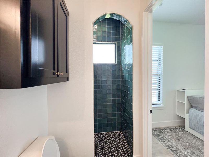 Full bath featuring a tile shower and wood finished floors