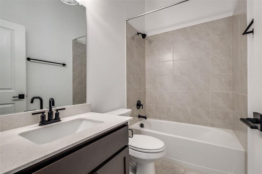 Full bathroom featuring tile patterned floors, vanity, tiled shower / bath combo, and toilet